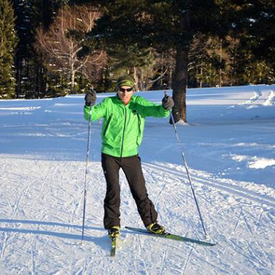 Cross country skiing man in green and child 